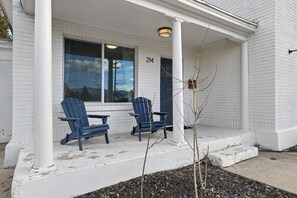 A white building with the number 214 on the door, two blue chairs on the porch, and a small tree in the foreground. - Charming 4-bedroom house with AC in Heber City (Heber City)