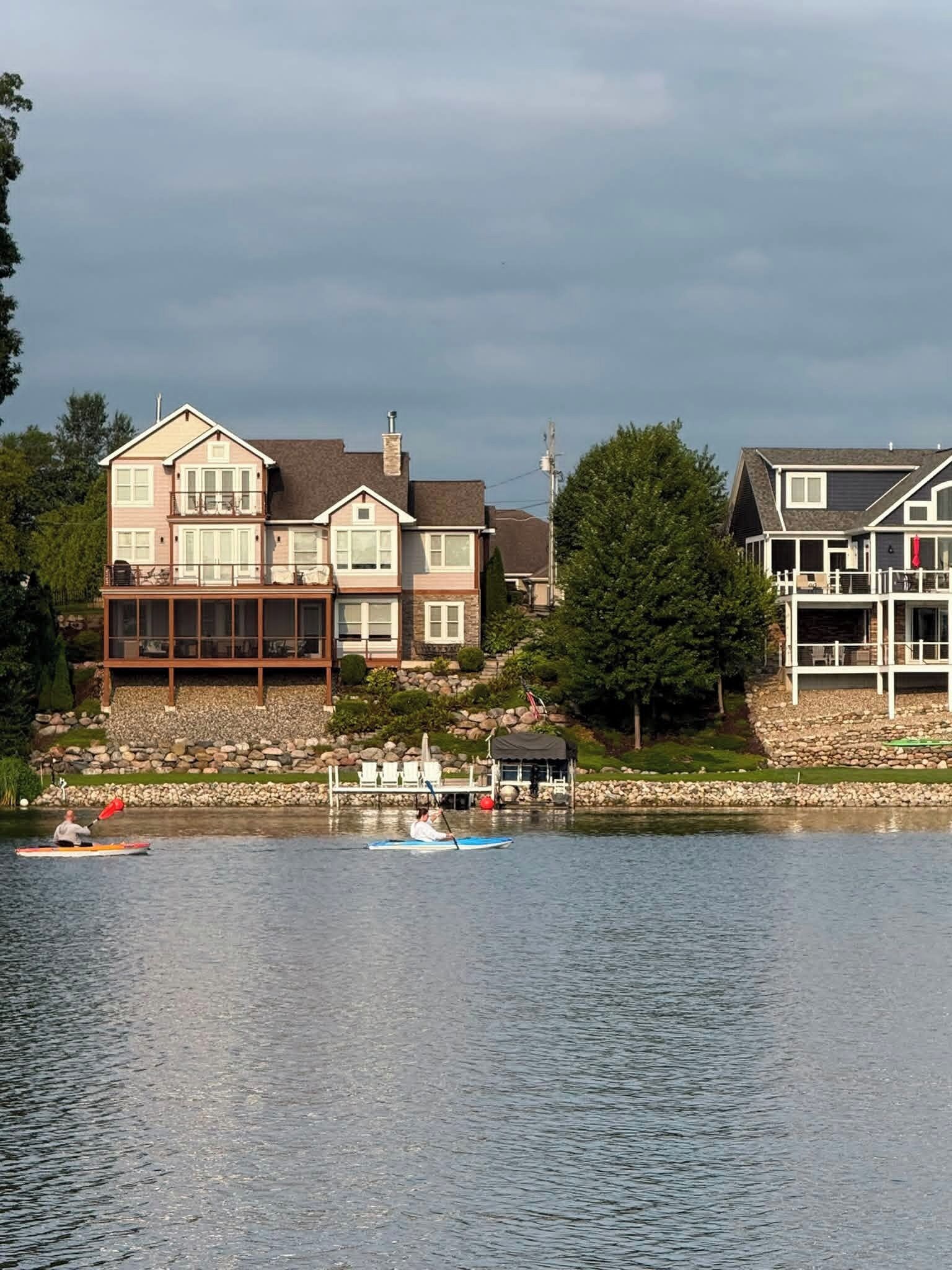 A lakeside property with a large house featuring multiple decks and a dock.