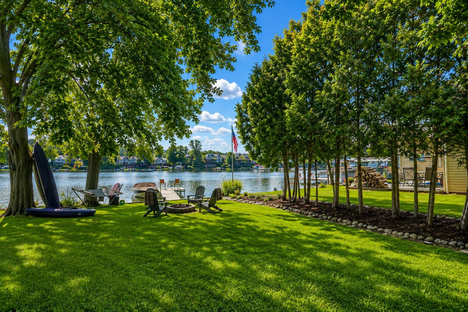 A lakeside outdoor area with a dock, chairs, and a fire pit.