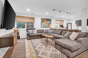 A modern living room with a sectional sofa, a coffee table, and a flat-screen TV. - North Boulder Elegance - Newlands Neighborhood (Boulder)