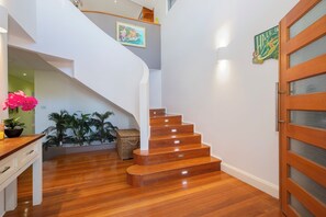 A wooden staircase leading to an upper floor, with a door on the right and a wall-mounted picture above. - Azure Horizon Beachfront Haven and Resort Style Pool (Stockton)