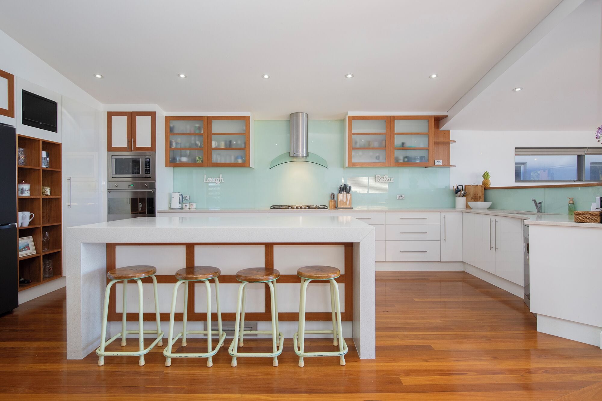 Una cucina moderna con isola centrale, sgabelli da bar e mobili in legno.