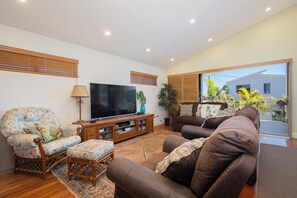A living room with a television, two sofas, a wooden coffee table, and a patterned rug. - Azure Horizon Beachfront Haven and Resort Style Pool (Stockton)