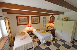 A room with two beds, a window with curtains, a radiator, and a checkered floor. - A beautiful, restored farmhouse in a quiet setting, with an enclosed garden for dogs and a stunning view. (Viviers)