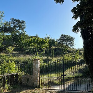 A gated entrance with a stone pillar, surrounded by greenery and trees. - A beautiful, restored farmhouse in a quiet setting, with an enclosed garden for dogs and a stunning view. (Viviers)