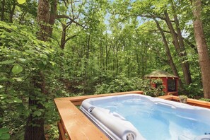 A hot tub surrounded by a wooden deck, set in a forested area with trees and greenery. - Welcome to the TreeHouse, Privacy right by downtown New Buffalo (New Buffalo)