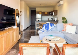 A modern living room with a sofa, a coffee table, and a television. - 3BR Tulum Condo with Garden Views (Tulum)