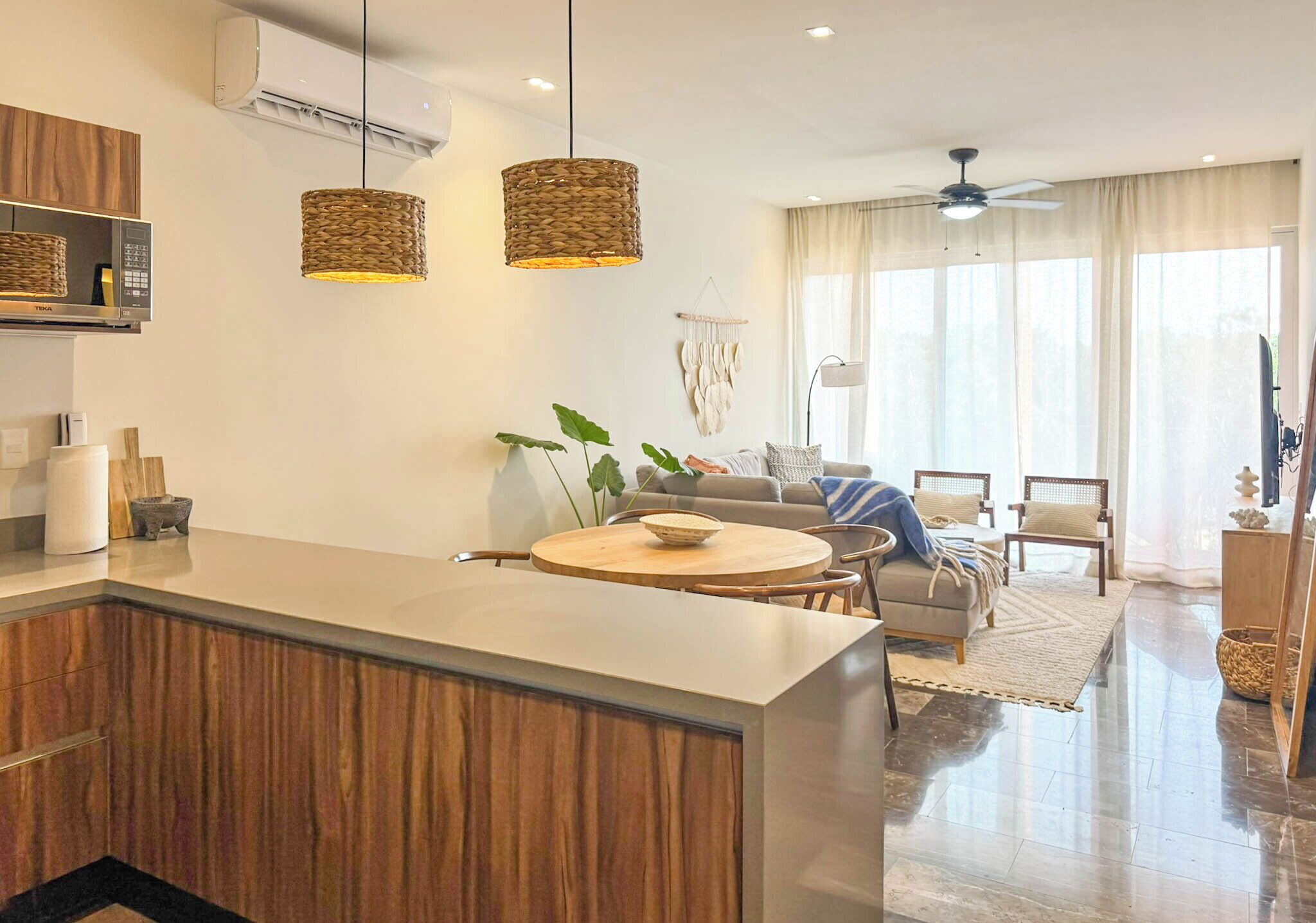 Una cocina moderna con una isla central, armarios de madera e iluminación colgante.
