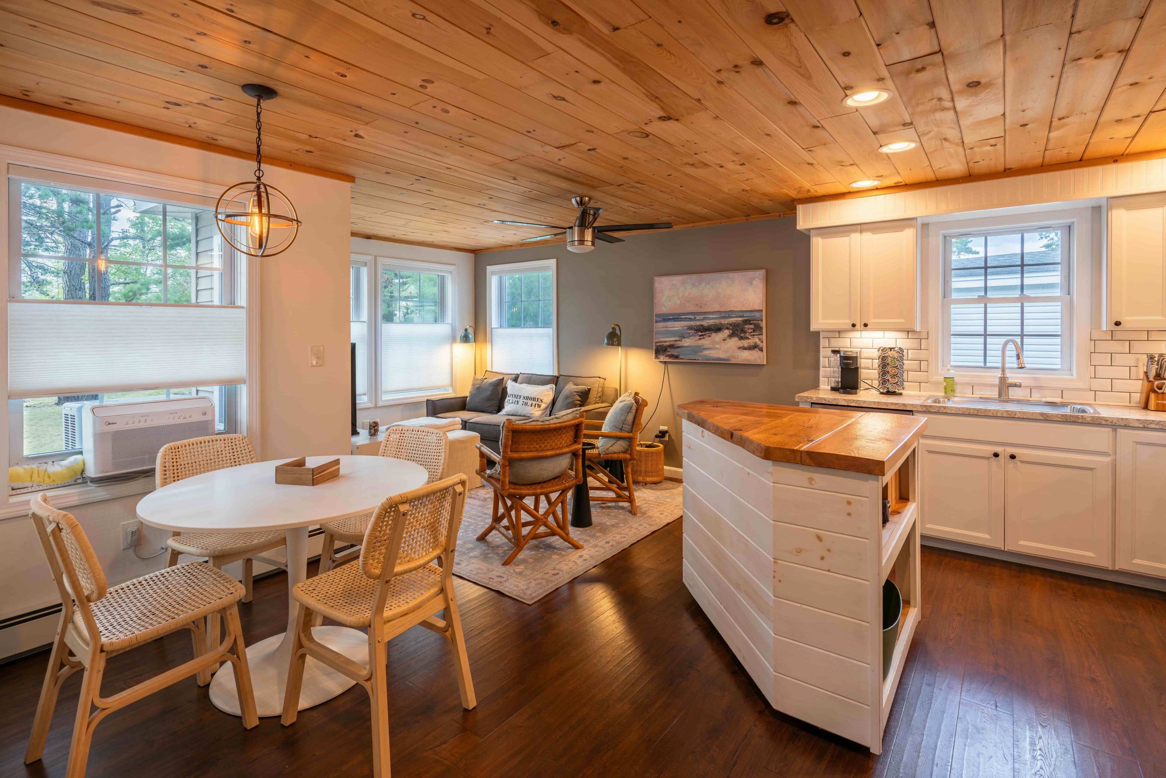 A cozy kitchen with wooden cabinets, a dining area with wicker chairs, and a view of the outdoors.