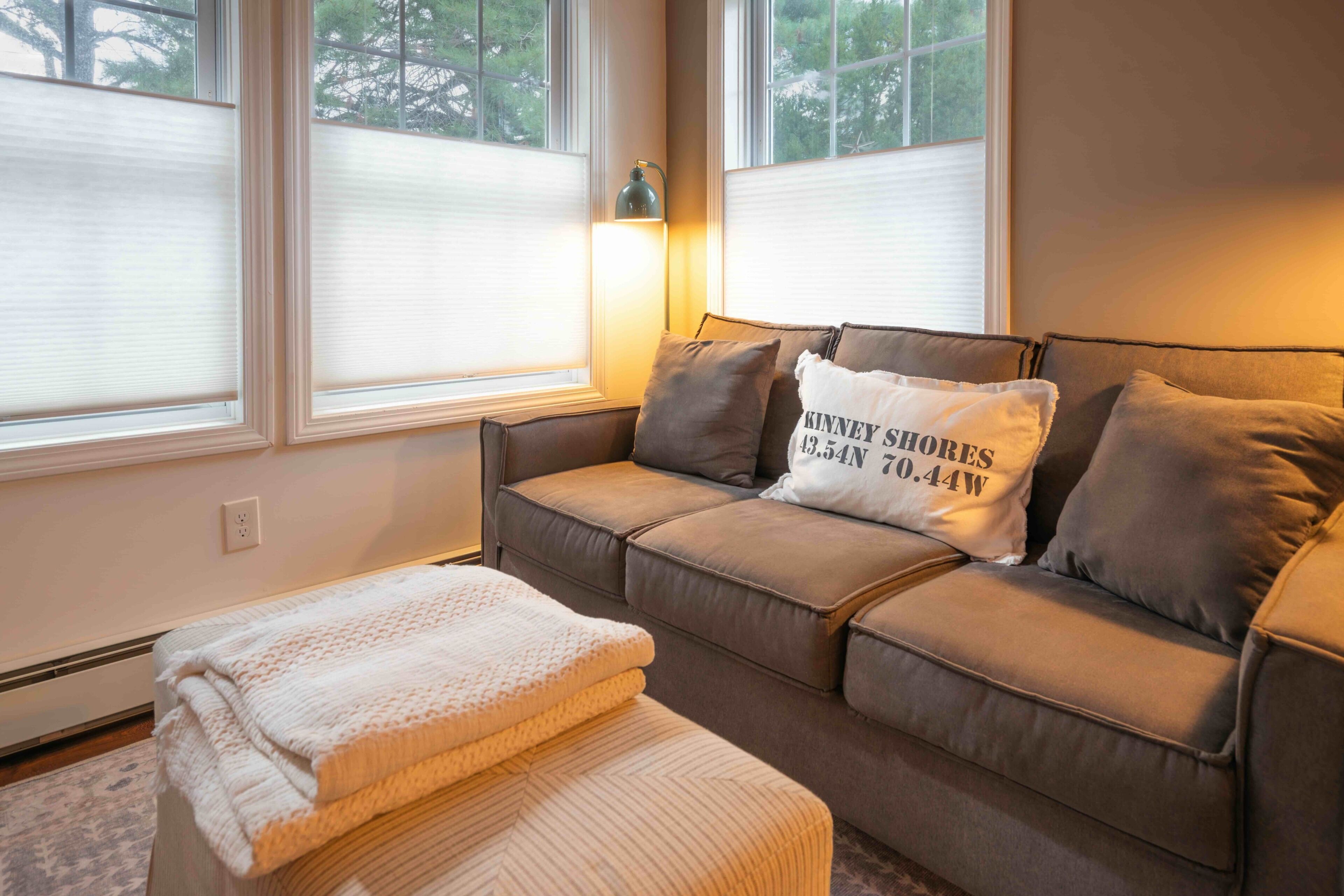 A cozy living room with a sofa, a throw blanket, and a pillow with text.