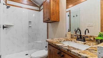 A bathroom with a shower, toilet, vanity with a sink, and a mirror.