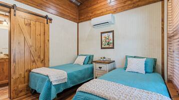 Una habitación con dos camas, paredes de madera, una puerta y un equipo de aire acondicionado.