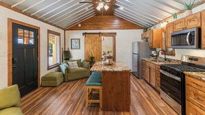 A compact kitchen with wooden cabinetry, a central island, and a built-in microwave.