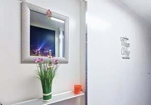 A room with a mirror, a vase with flowers, and a shelf with a candle. - N&J - LA FENICE - Balcony - Close sea (Nice)