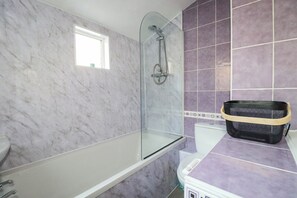 Ein Badezimmer mit Duschkabine aus Glas, einer weißen Badewanne und violetten Fliesen.