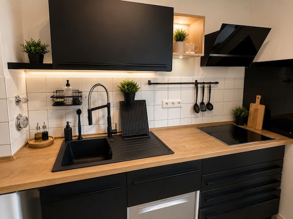 A modern kitchen with a black countertop, stainless steel appliances, and a black backsplash.