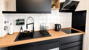 Eine moderne Küche mit einem schwarzen Spülbecken, einem Edelstahlarmaturen, schwarzen Schränken und einer Holz Arbeitsplatte.