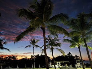 A beach scene with palm trees and a sunset. - HGTV remodeled and decorated this concrete Key Largo Coastal Home monthly rental (Key Largo)