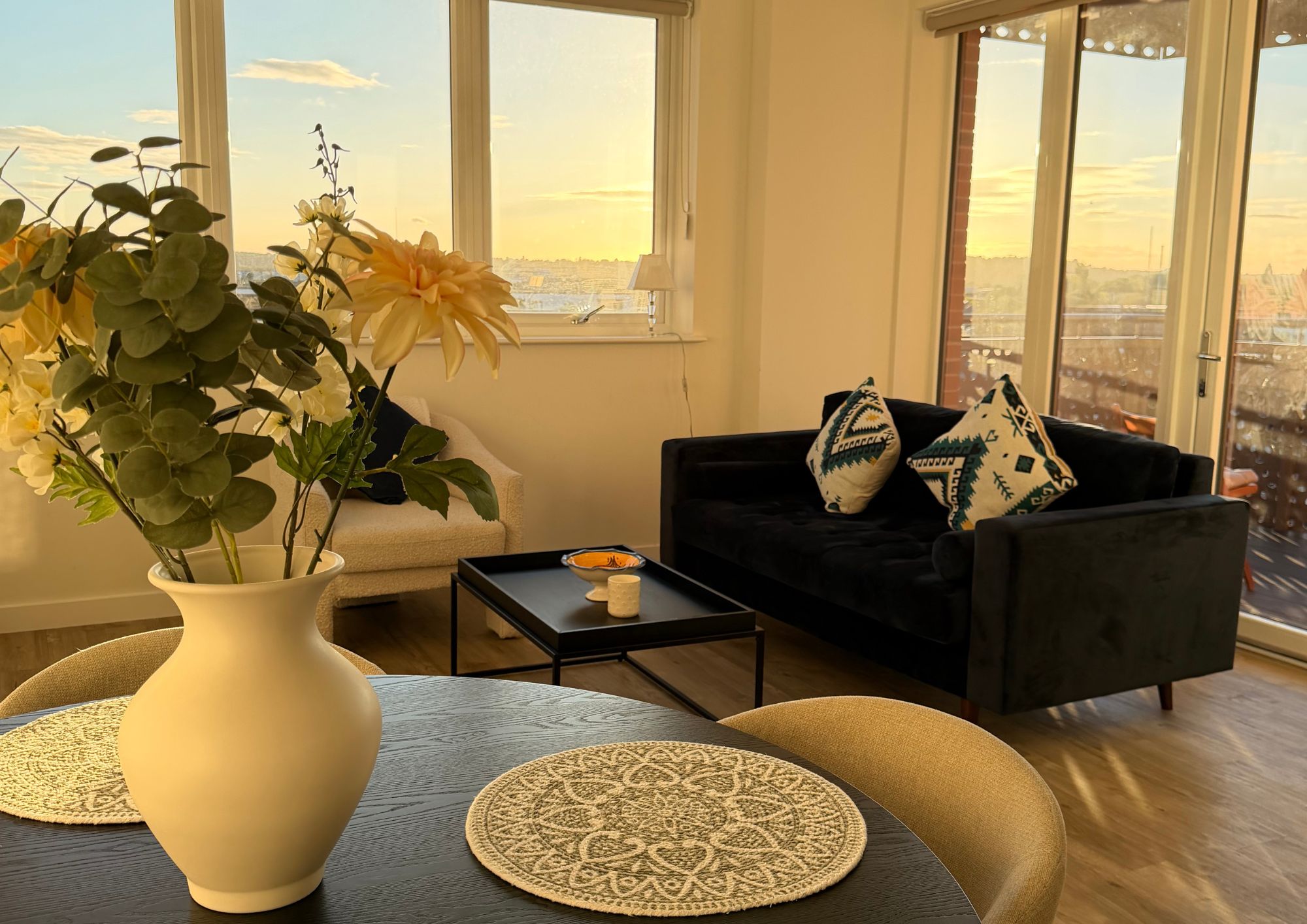 A modern living room with a sofa, a coffee table, and a vase with flowers.
