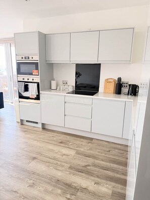 Eine moderne Küche mit weißen Schränken, einem eingebauten Ofen und einer schwarzen Induktionskochplatte.