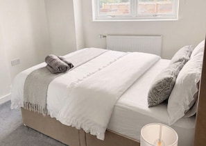 Ein Schlafzimmer mit Bett, Fenster, Heizkörper und Lampe.