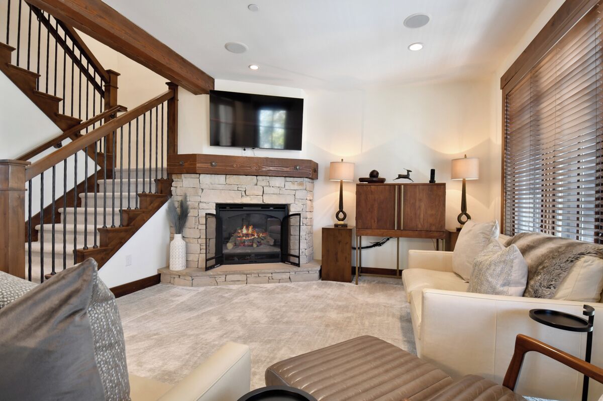 A living room with a fireplace, a staircase, a sofa, and a television mounted on the wall.