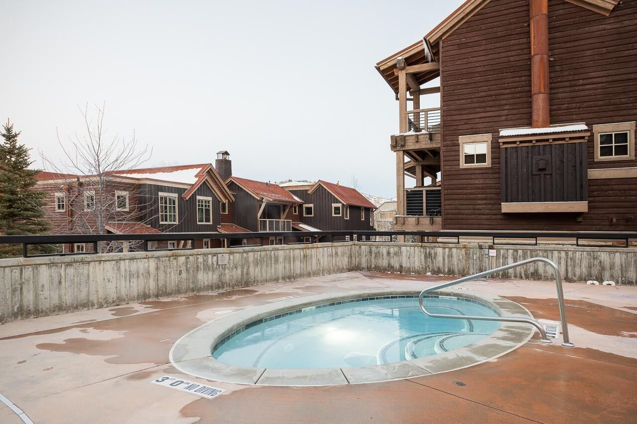 Une piscine avec un escalier en métal, entourée d’une terrasse en béton.