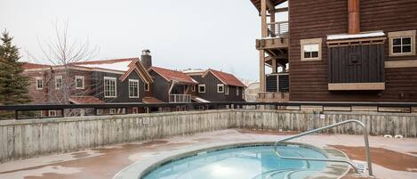 Une piscine avec un escalier en métal, entourée d’une terrasse en béton.