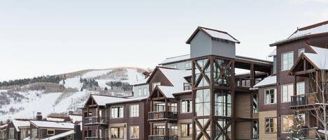 A multi-story hotel with a wooden exterior and large windows, set in a snowy mountainous area.