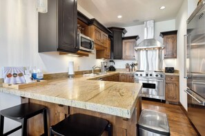 A modern kitchen with granite countertops, stainless steel appliances, and wooden cabinetry. - Silver Star 802 | Ski-in/Out | Hot Tub (Park City)