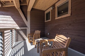 Una terraza de madera con barandilla, una mesa y cuatro sillas.