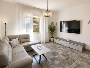 Ein modernes Wohnzimmer mit einer Eckcouch, einem Couchtisch, einem Fernseher und einer Zimmerpflanze.