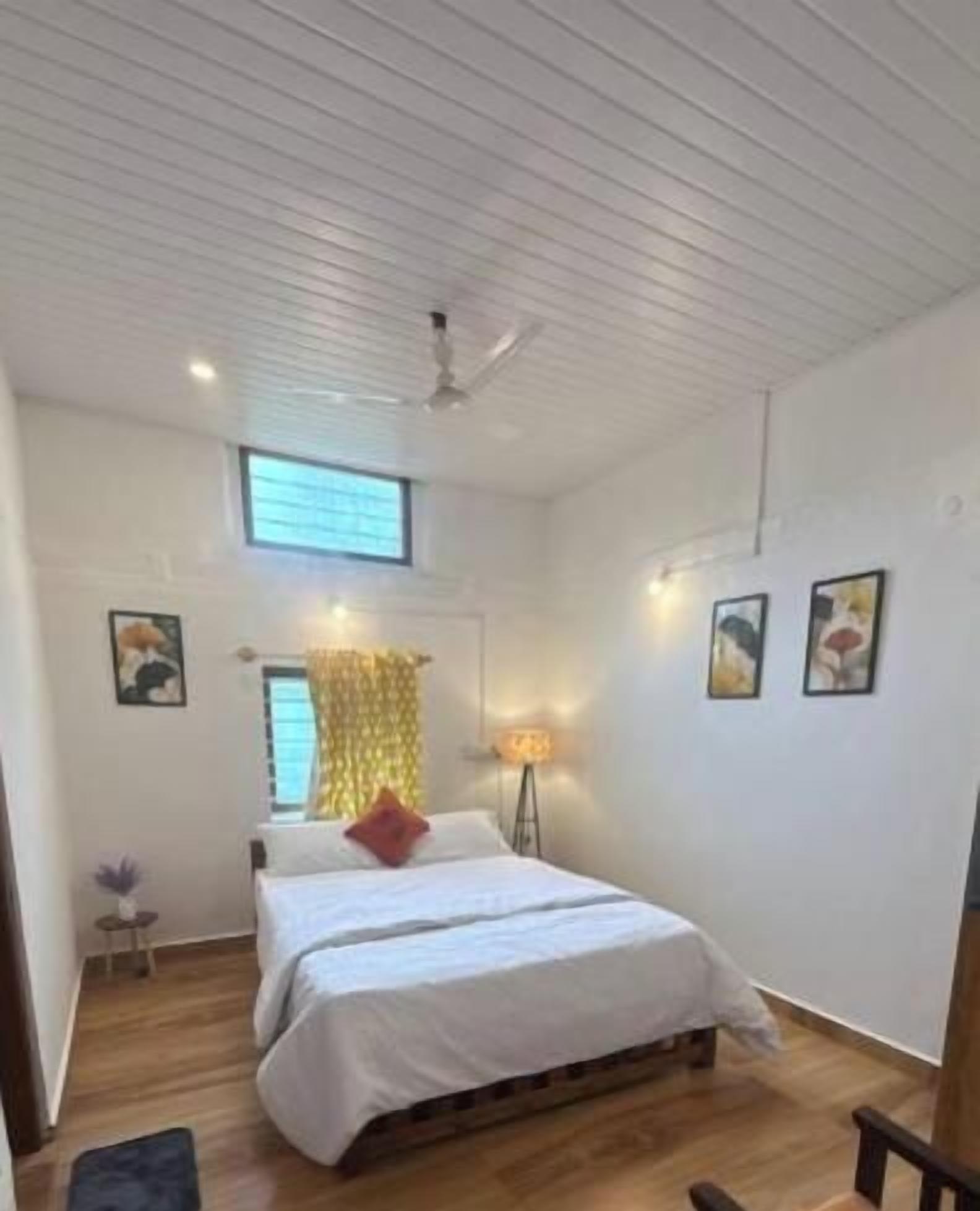 A bedroom with a bed, a window, a floor lamp, and a ceiling fan.