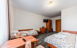 A hotel room with two beds, a desk, a television, and a wardrobe. - Apartment for 3 People, Rewal (Rewal)