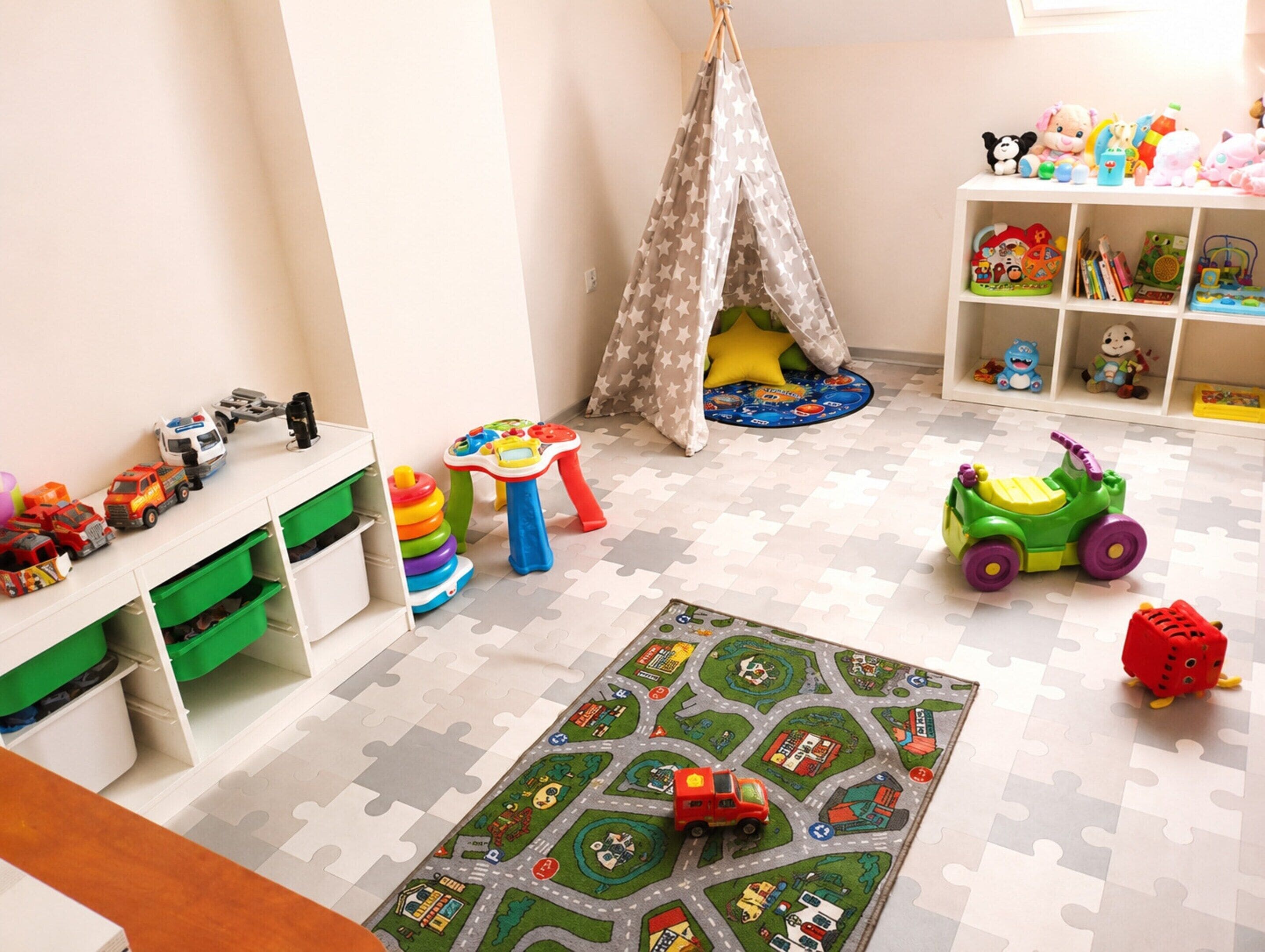 A child's playroom with a puzzle mat, toys, and storage units.