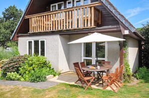 A two-story house with a balcony, a patio with a table and chairs, and a garden area. - No.122 Hengar Holiday Park (Bodmin)