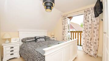 A bedroom with a bed, bedside table, lamp, and a view of the outside.