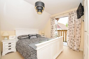 A bedroom with a bed, bedside table, lamp, and a view of the outside. - No.122 Hengar Holiday Park (Bodmin)