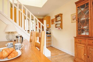 A kitchen with a wooden staircase, a dining table with croissants, and a cabinet with glass doors. - No.122 Hengar Holiday Park (Bodmin)