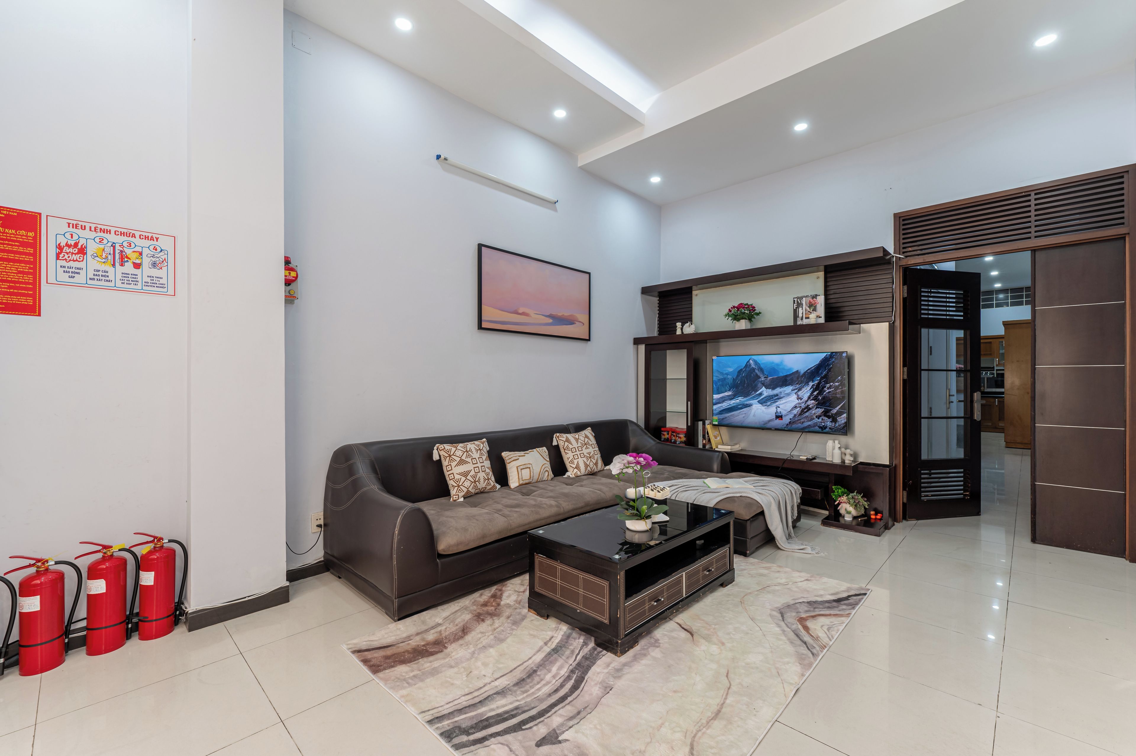 A modern living room with a sofa, coffee table, flat-screen TV, and a fireplace.