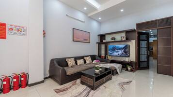 A modern living room with a sofa, coffee table, flat-screen TV, and a fireplace.