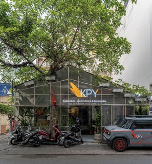 A commercial building with a glass facade, signage for KPY Architecture, and parked scooters and a car outside. - NIDOVA SAIGON - D1 Townhouse Residence (Ho Chi Minh City)