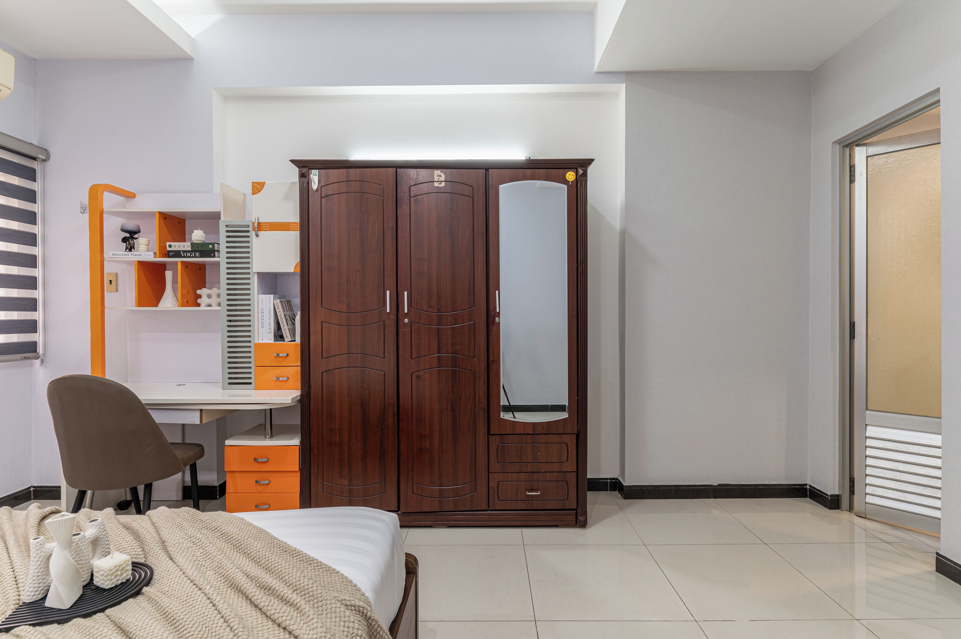 Een slaapkamer met een bed, een bureau, een kledingkast en een stoel.