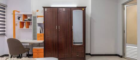 A bedroom with a bed, a desk, a wardrobe, and a chair.
