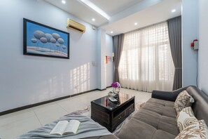 A modern living room with a sofa, a coffee table, and a painting on the wall. - NIDOVA SAIGON - D1 Townhouse Residence (Ho Chi Minh City)