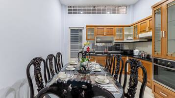 A dining area with a table set for four, surrounded by ornate chairs, in a kitchen with wooden cabinets and modern appliances.