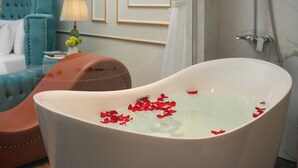Une salle de bain avec une baignoire sur pieds, une douche et un lit avec une tête de lit bleue.