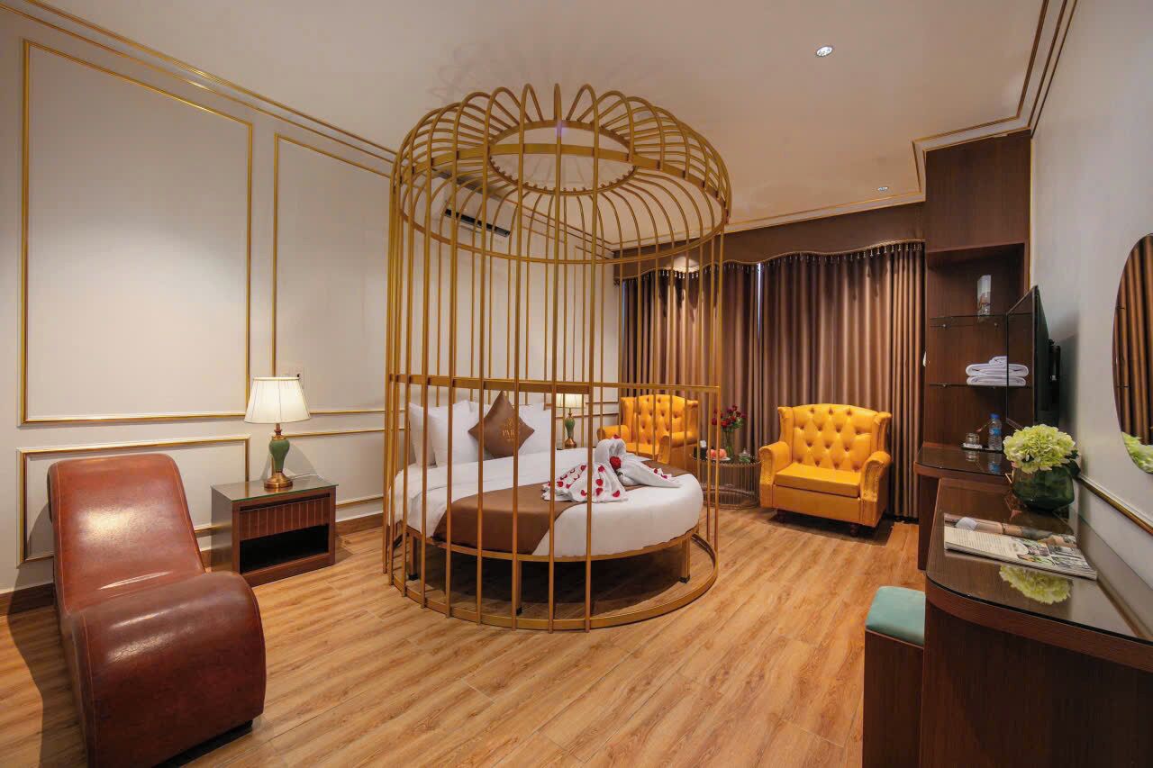 Habitación de hotel con cama, zona de estar con sillón, escritorio y televisor.