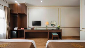 Une chambre d’hôtel avec deux lits, un bureau, une télévision, un miroir et un petit placard.