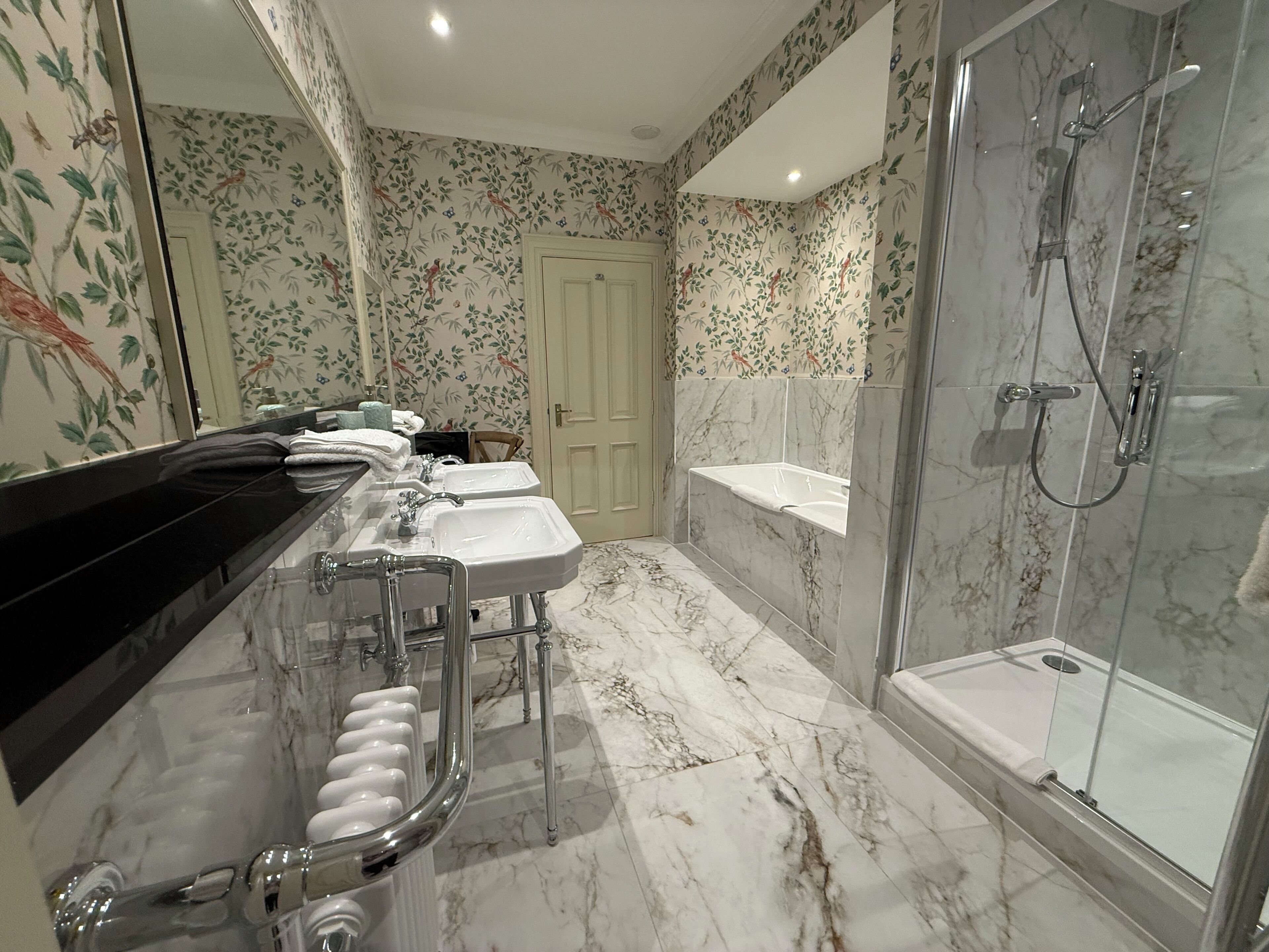 Un baño con suelo de mármol, ducha, lavabo e inodoro.
